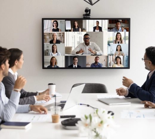 Cut-out image of Fabrick's head of Digital Content, Kate Aristides positioned next to a laptop showing numerous people's faces on a laptop screen