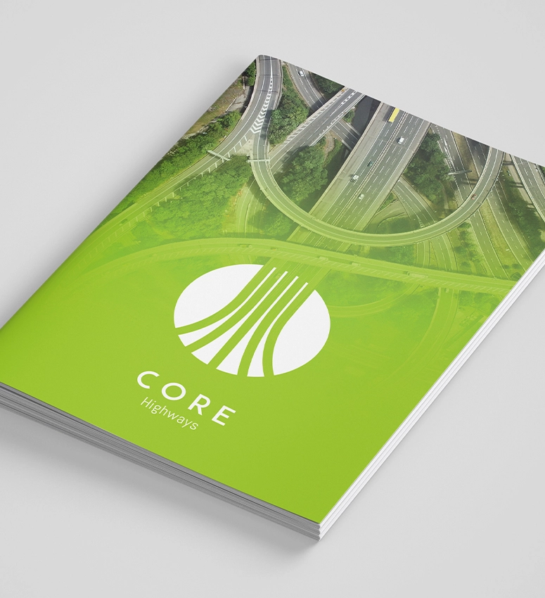 A laptop screen showing the new website design for Core Highways Group and a pile of business cards showing the new branding and logo Fabrick's creative team designed
