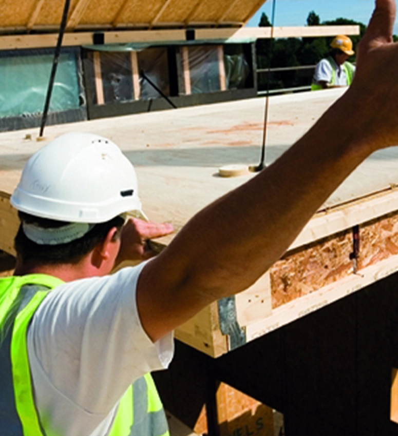 Construction site workers aiding the delivery of off-site timber panels 