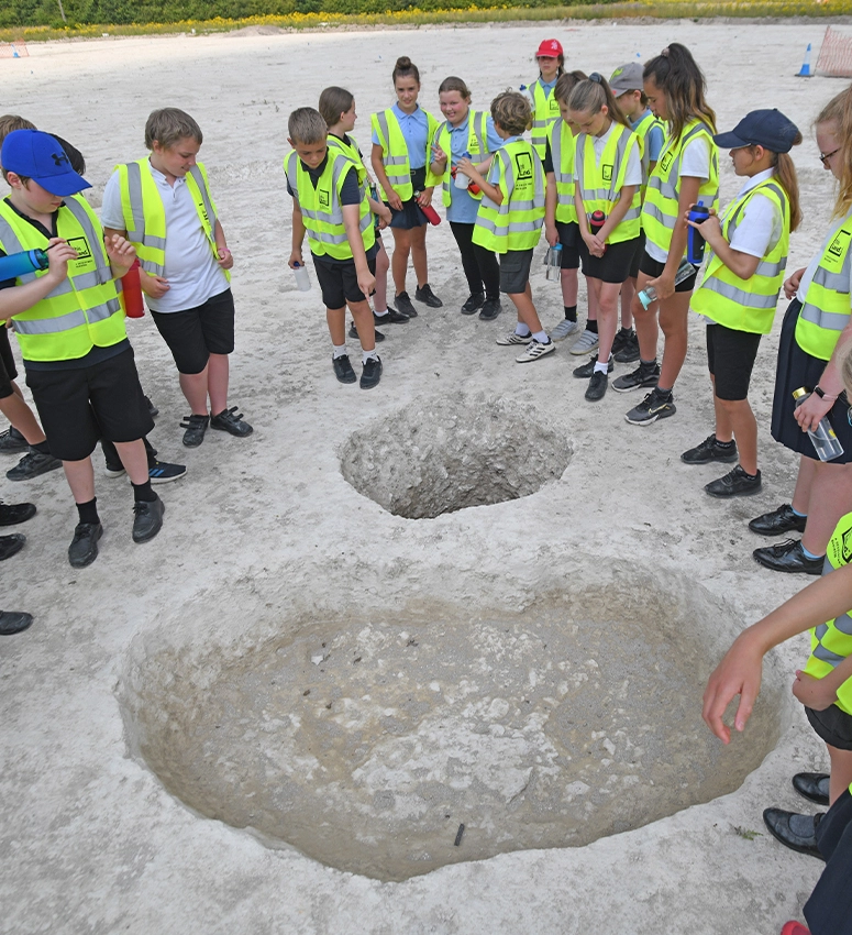 School children from Burwell dressed in construction PPE visiting an archaeological dig where bones from the bronze age are discovered